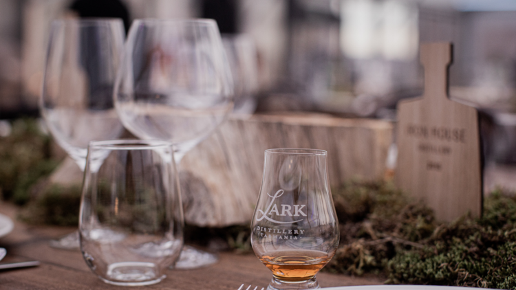 A wooden table with a dram of Lark whisky