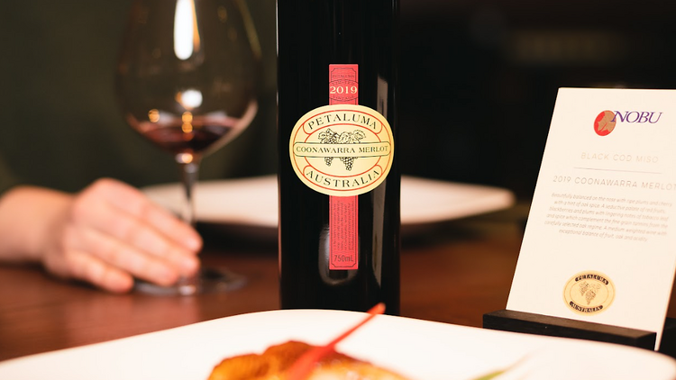 A salmon dish and a bottle of wine and a wine glass on a dining table.