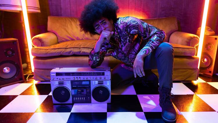 A man with an afro posing next to a boombox.