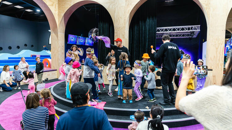 A large group of children dancing on a stage.