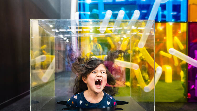 A child playing in a translucent box. 