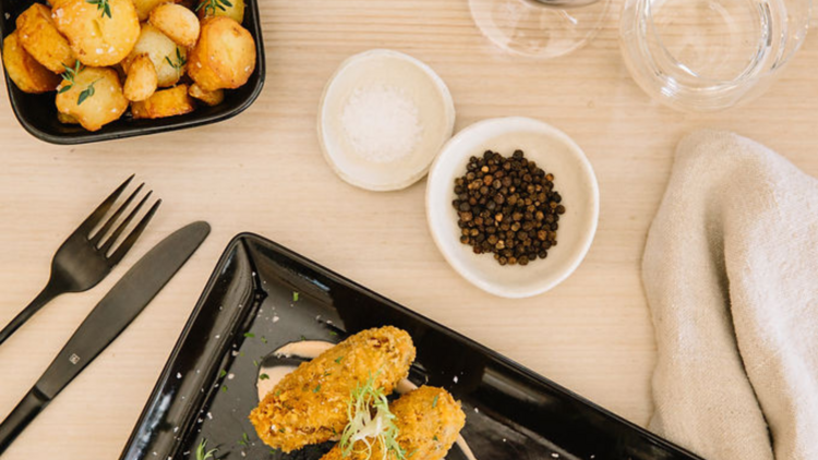 Flat lay of croquettes, peppercorns, roasted potatoes and wine