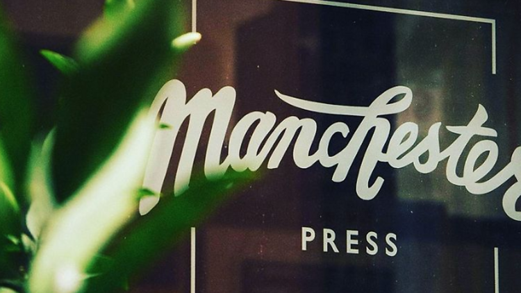 The entry of Manchester Press' glass window, with a sign with their logo