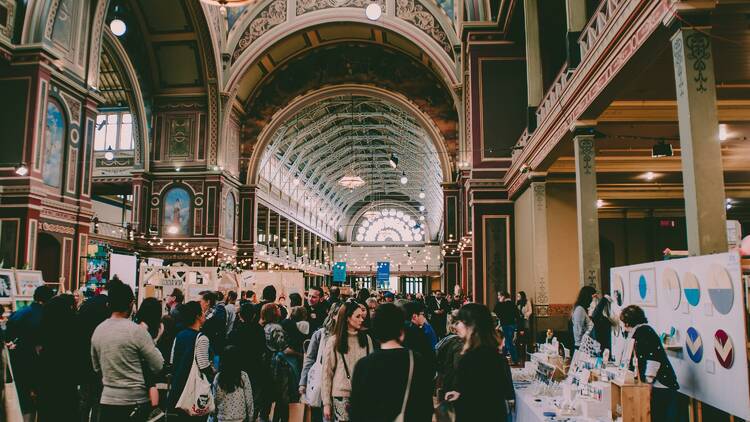 An ornately decorated exhibition building packed with people and stalls.