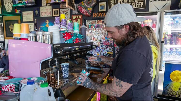 A barista with a tattooed arm makes coffee at Café Royal, Perth