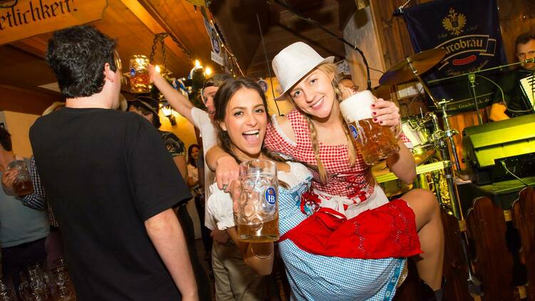 Two women at an Oktoberfest party holding steins.