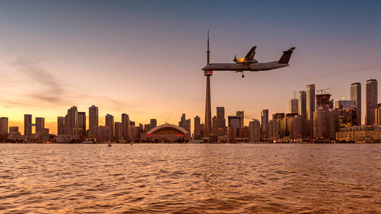 Toronto skyline at sunset and plane lands to Billy Bishop City Airport