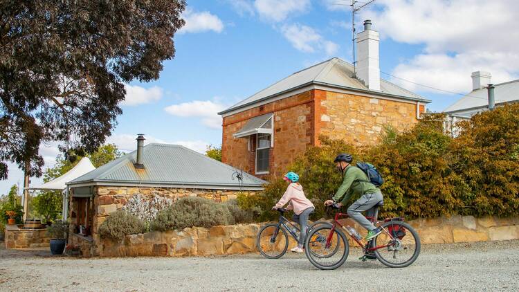 A father and child bike past the brick Crabtree Wines tasting room