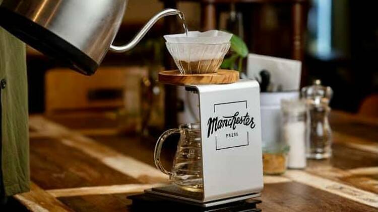 Water is poured into a coffee filter, which is filtering out coffee in a slow drip system