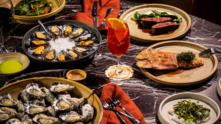 A flat lay of oysters, steak, kingfish and salad on a marble table