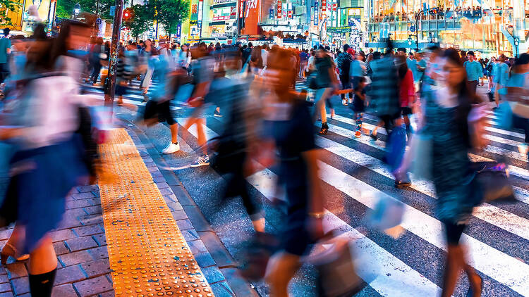 People and traffic cross the famous scramble intersection in Shibuya, Tokyo, Japan