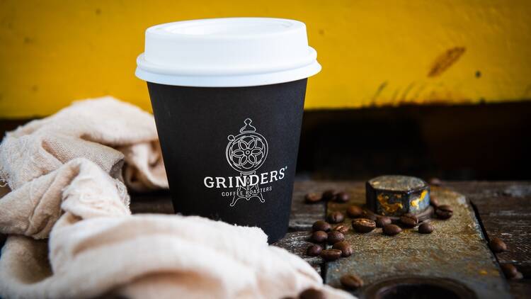 A cup of Grinders coffee and some beans