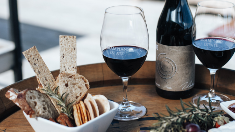 A barrel with a bottle of wine, two glasses and nibbles.