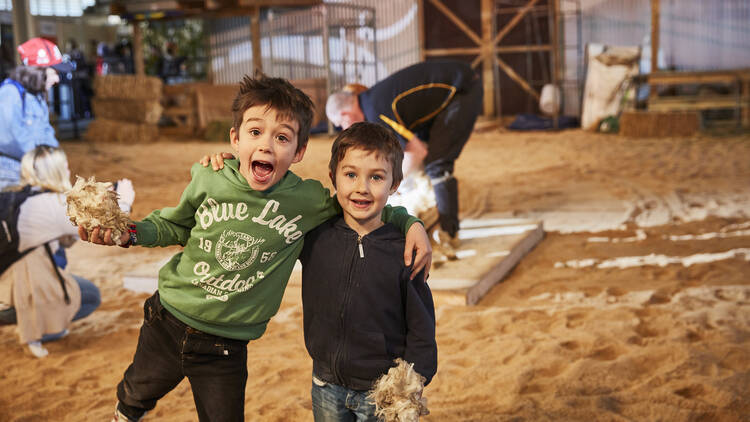 Two kids playing in a sand pit. 