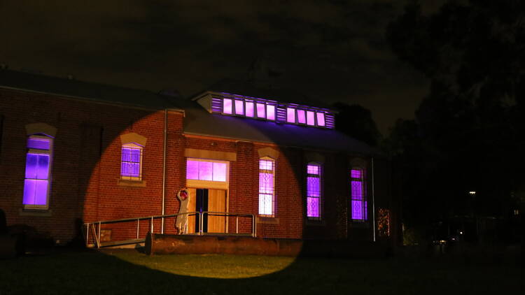 A building is lit up in a red and purple spotlight