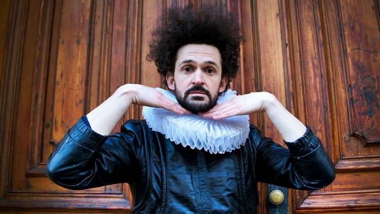 A man with frizzy black hair wearing an Elizabethan ruff