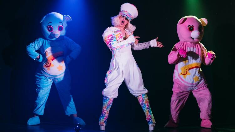 A drag performer with two dancers dressed as giant teddy bears