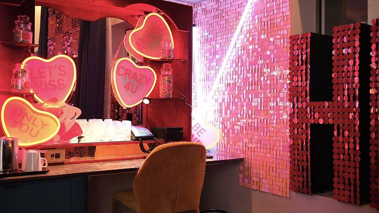 A desk and mirror with candy heart signs and jars of lollies.