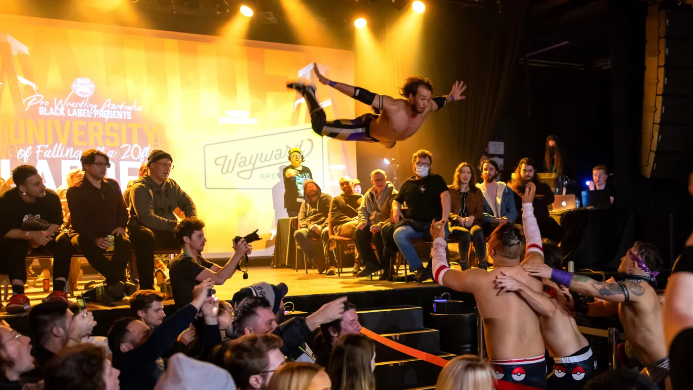 A wrestler flies through the air at a Pro Wrestling Australia match