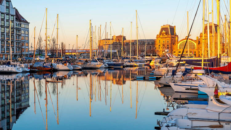 The yacht harbor of Oostende (Ostend) with train station at sunset, Belgium.