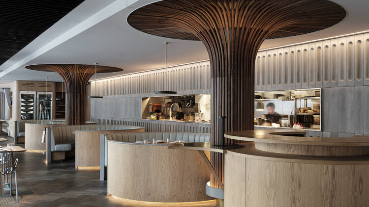 A restaurant space with round timber booths, warm strip lighting, wood flooring and an open section that looks into the kitchen.