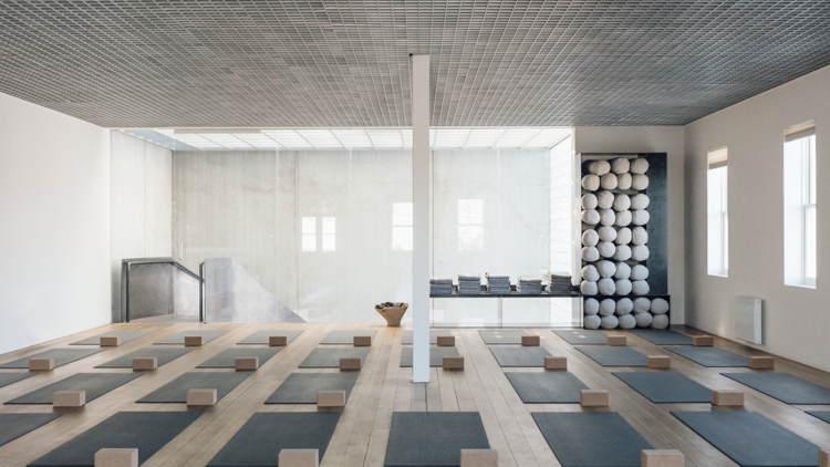 A yoga studio featuring a floor with heaps of yoga mats and blocks.