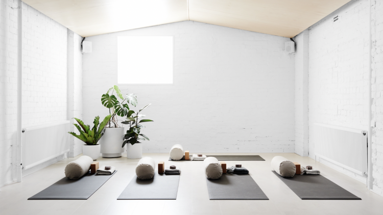 A light-filled yoga studio with five yoga mats positioned on the floor.