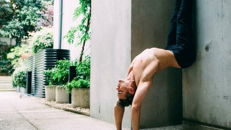 A man practising yoga in a courtyard.