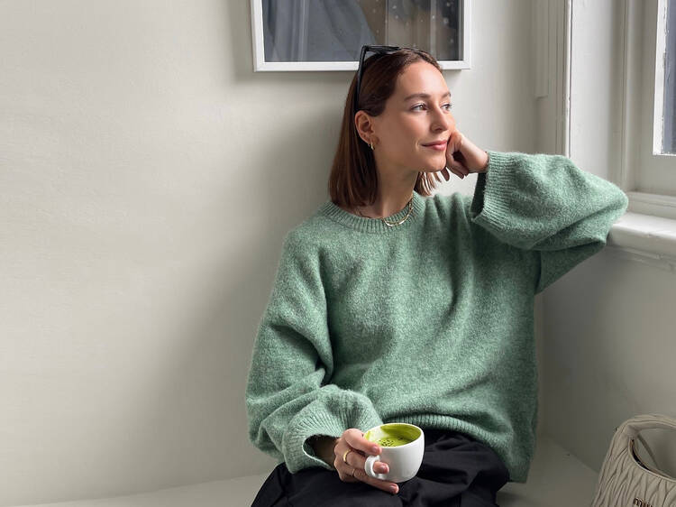 Content creator Jess Alizzi sitting in a café with a matcha latte.