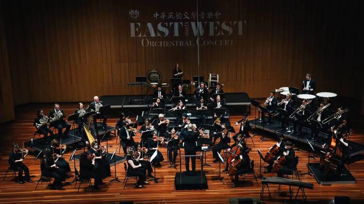 A wide shot of an orchestra in a concert hall.