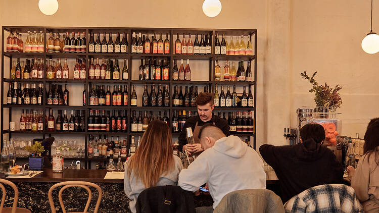 A bartender serving a couple seated at the bar.