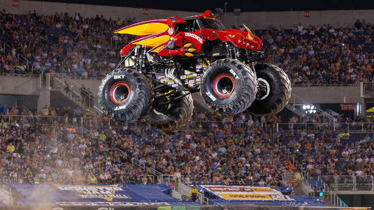 A red monster truck flying through the sky.