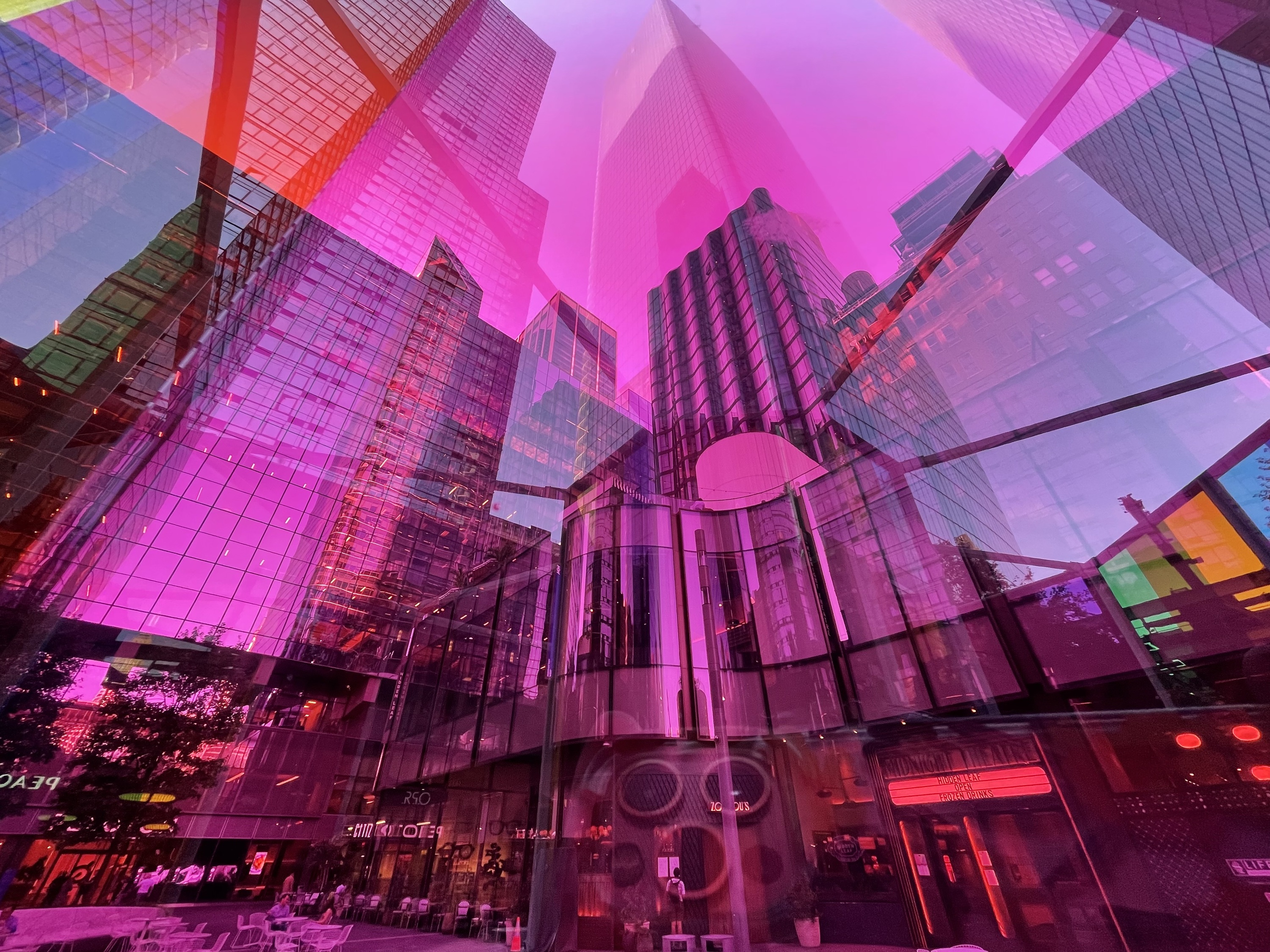 The city's skyscrapers as seen through a transparent pink panel.