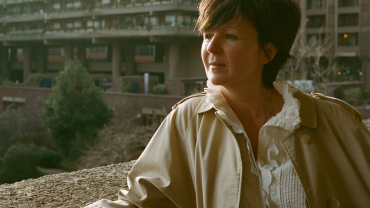 Award winning author Olivia Laing stares off camera against a building backdrop