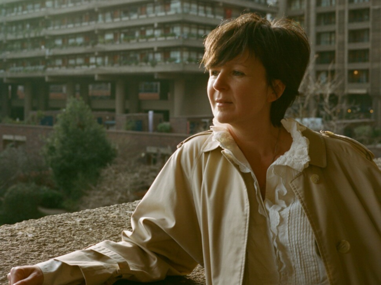 Award winning author Olivia Laing stares off camera against a building backdrop