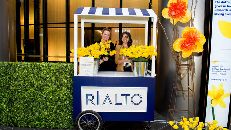 Two women selling daffodils at a hotel lobby.