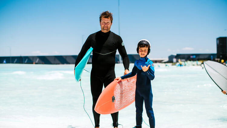 A father and son playing at an outdoor surf park.