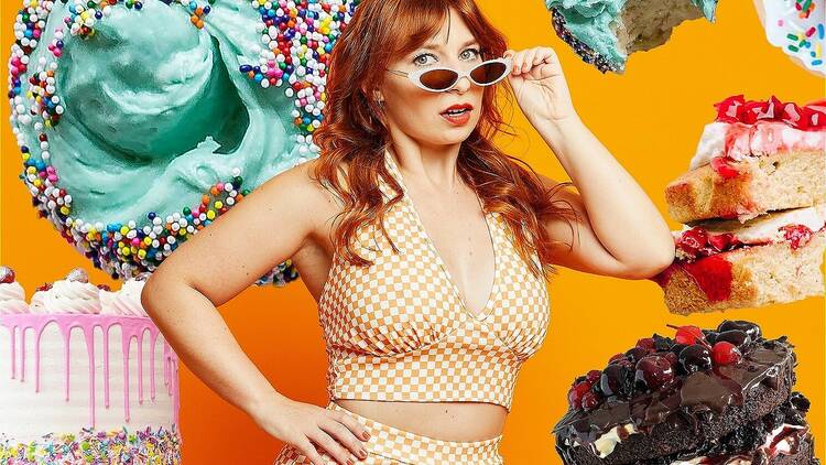 Comedian Robyn Reynolds wearing a yellow-and-white check two-piece outfit and sunglasses surrounded by elaborate cakes.