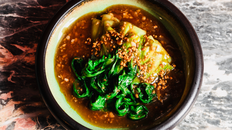 A bowl of wilted greens and peanut sauce