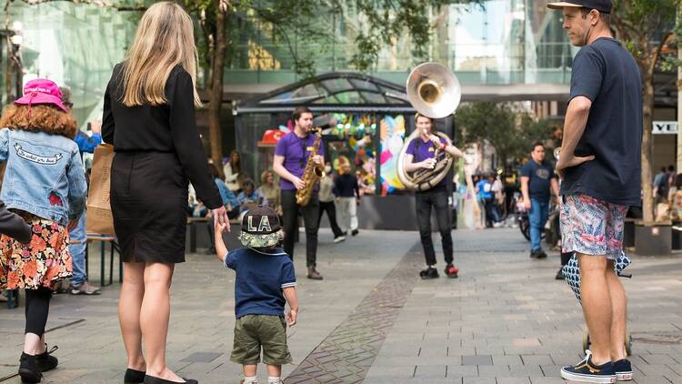 A family watches a band perform on Pitt Street