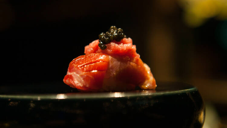 A piece of otoro nigiri topped with caviar.