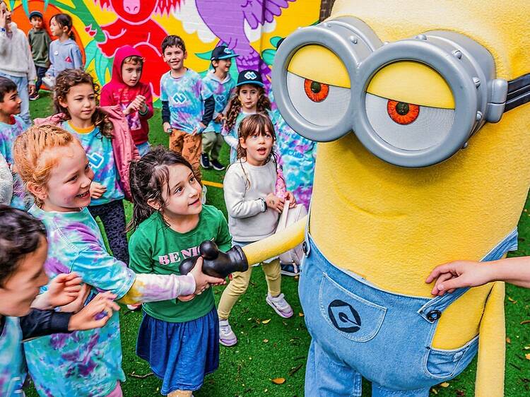 Kids are shaking hands with a giant yellow minion