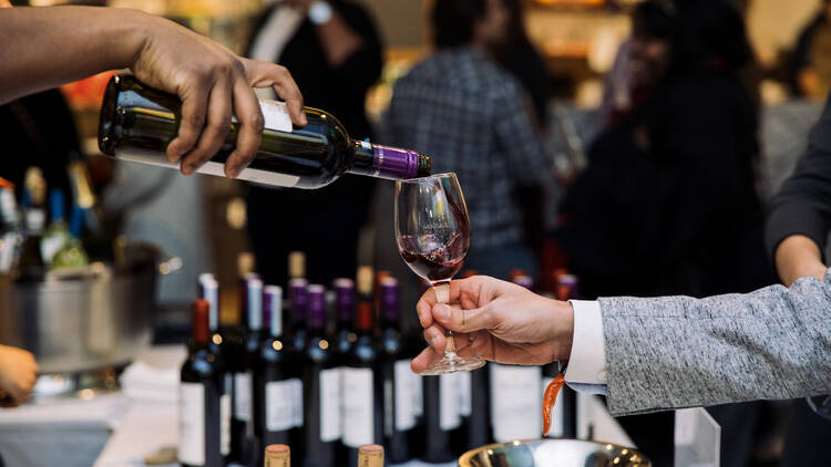 A person receives a pour of red wine at Eataly