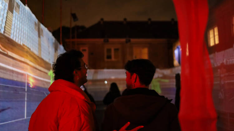 Two people walk through the Convent illuminated in red light