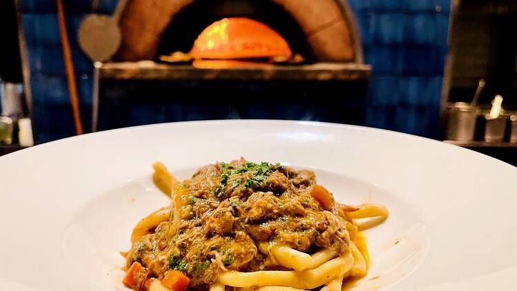 A bowl of pasta in front of an oven.