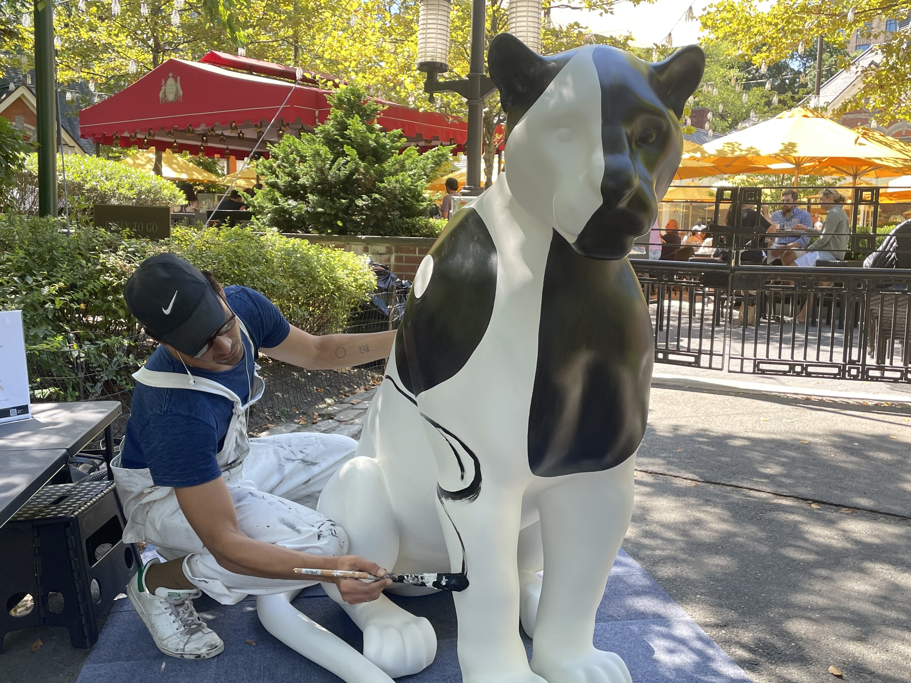 Artist Pedro Silva paints a jaguar sculpture in black and white.