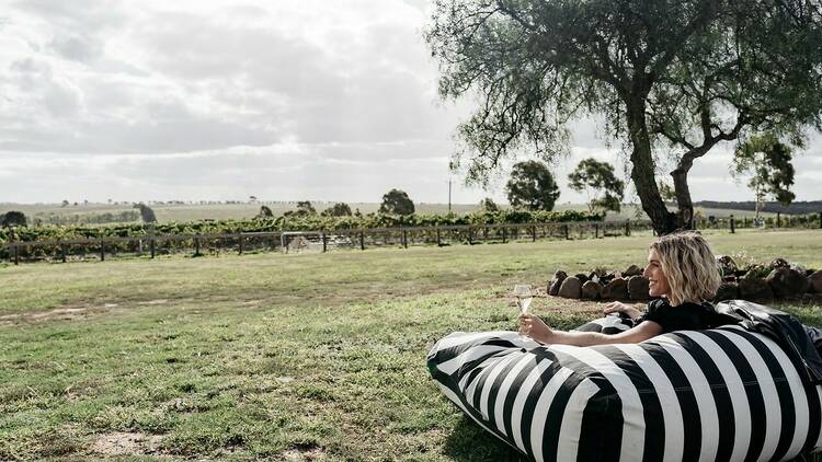 A woman enjoying a glass of wine outdoors at a winery