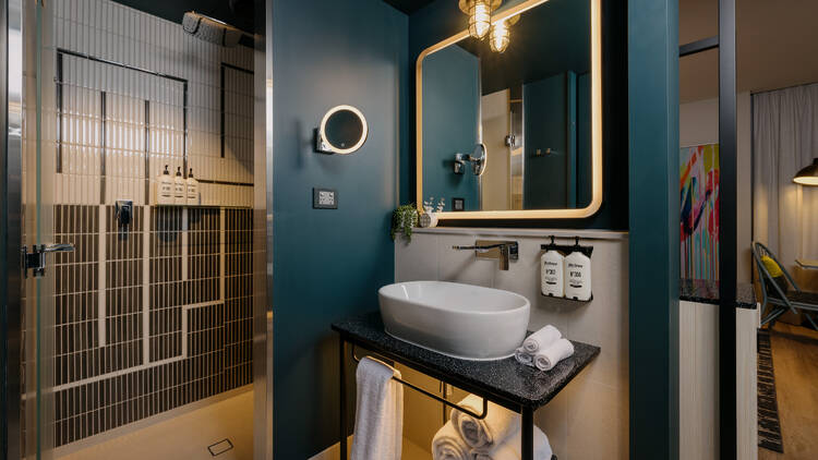 A bathroom at Hotel Indigo, with blue paint surrounding the sink, and a black and white tile shower