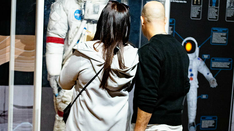 A man and a woman observing a spacesuit.
