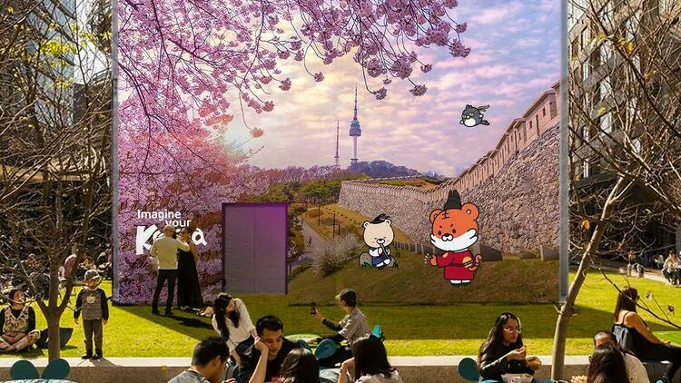 A large cube in an outdoor setting with an image of Korea on it plus cute characters